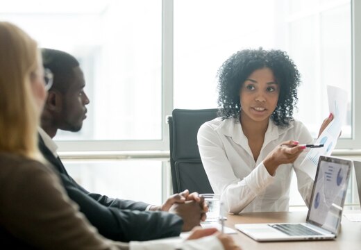 Woman explaining graphs to two colleagues.