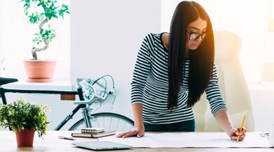 Woman writing plans on a large sheet of paper.