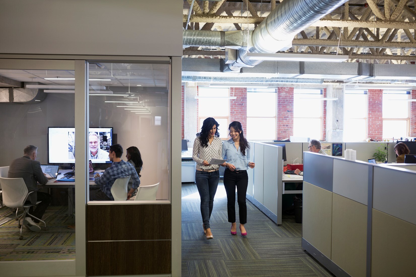 Office and conference room with employees reviewing digital and hard-copy files.