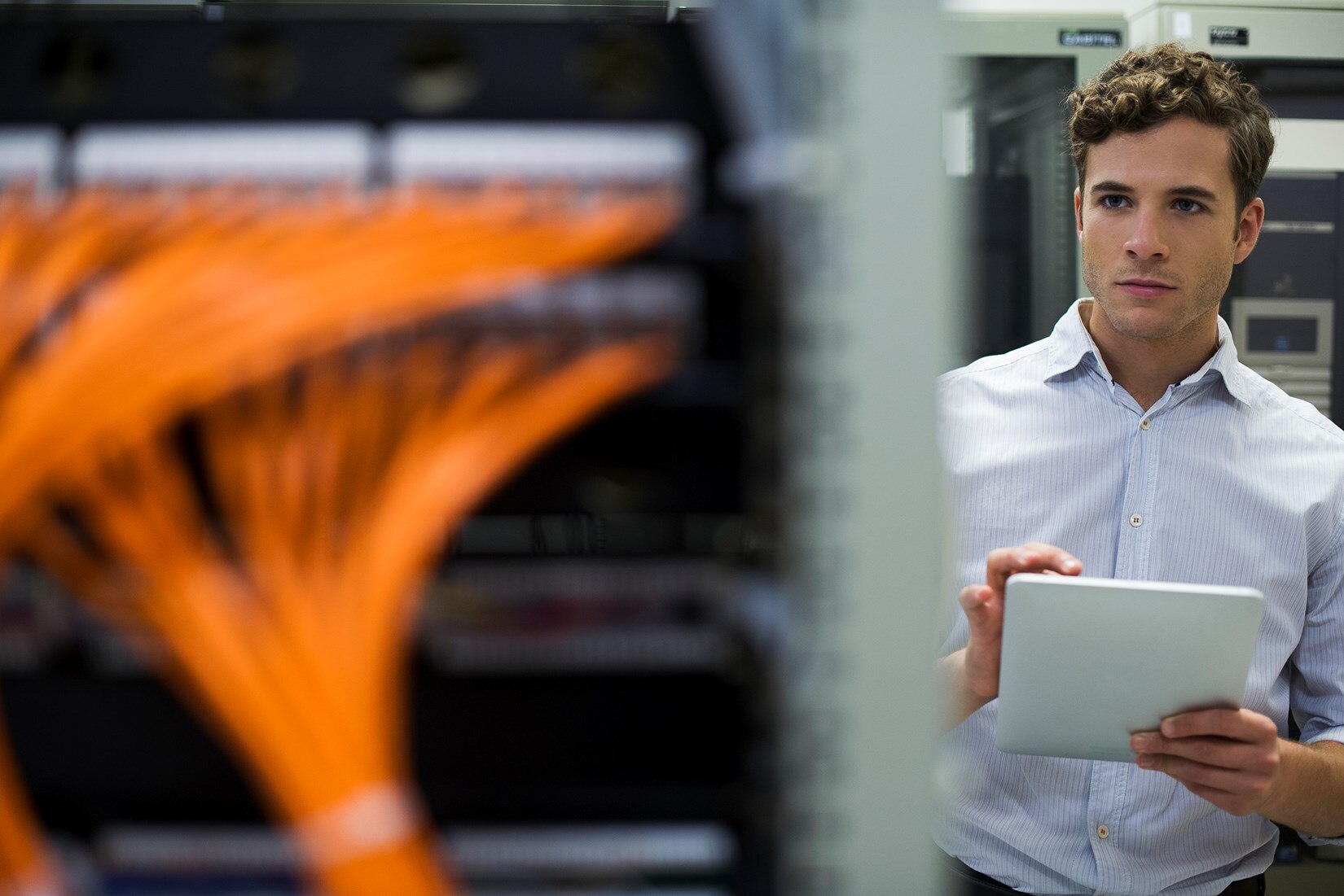 Man working on tablet in front of servers.